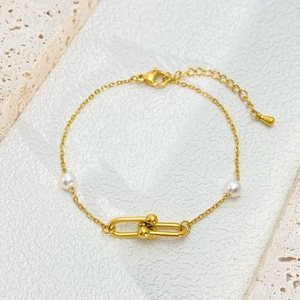 Detailed shot of golden horseshoe clasp and white pearls on a minimalist link bracelet