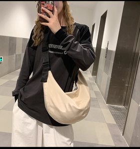 Detailed view of beige nylon dumpling bag with adjustable strap worn by a model