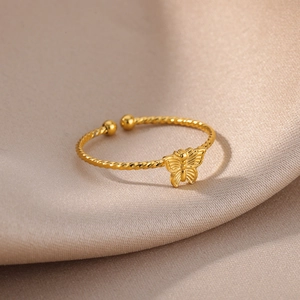 Detailed close-up of a twisted gold butterfly ring on a satin background