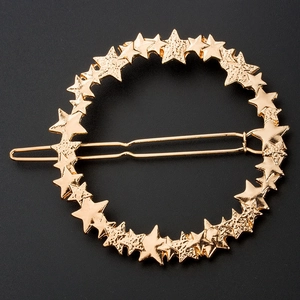 Detailed view of a gold star-shaped alloy hair clip on a matte dark gray background