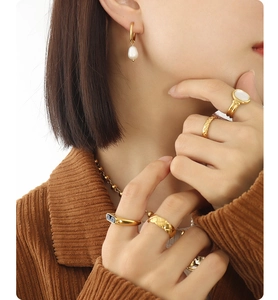 Close-up of gold freshwater pearl hoop earrings and layered vintage stacking rings