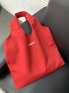 Detail of red canvas simplicity tote bag showing high-capacity design on leather surface