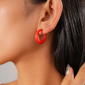 Close-up of a matte red acrylic C-shape hoop earring worn by a model for a chic look
