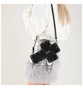 Detail of gothic cross-shaped handbag with silver rivets, skull accent, and metal chains