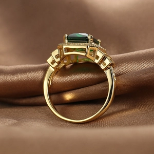 Vintage gold ring with emerald-cut green zircon and geometric diamond accents on silk