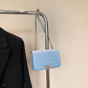 Detail of light blue quilted leather bag showing gold twist lock and chain strap