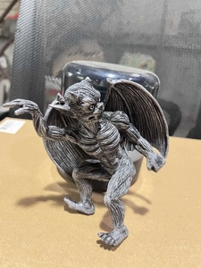 Detail of gargoyle figurine with wings in a crouched pose with stone texture resin