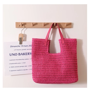 Macro detail of the pink woven straw tote bag texture and reinforced leather handle