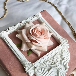 Close-up of pink leather handbag featuring a 3D rose flower and Baroque relief frame detail