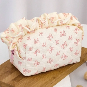 Neceser beige acolchado con lazos rosas y volantes sobre bandeja de madera