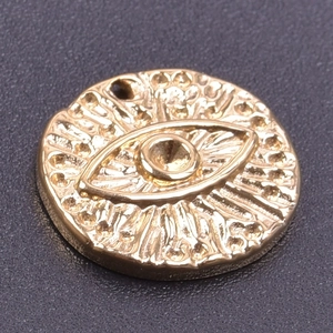 Macro shot of 18k gold plated evil eye charm with radial texture and embossed details