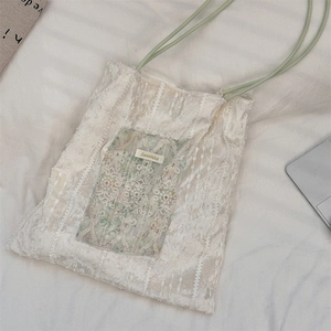 Détail d'un sac cabas en dentelle plissée beige avec poche florale et étiquette de marque