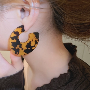 Close-up of model wearing C-shaped acrylic leopard print earrings with a vintage style