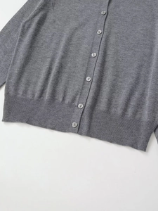 Close-up of grey knit cardigan featuring button closure and ribbed hem detail
