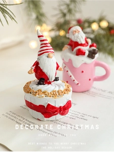 Detailed view of resin Christmas gnome on cupcake base with blurred holiday lights