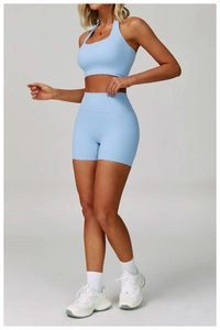 Detail of light blue high-waist yoga shorts and halter sports bra set with matte texture