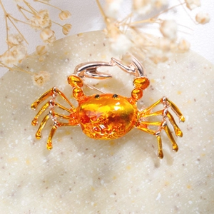 Detailed close-up of a crab brooch with amber shell and rose gold legs on stone