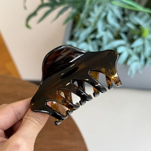 Gros plan de la pince à cheveux en résine marron foncé avec texture ambrée