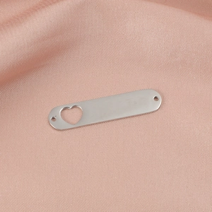 Close-up of heart cutout stainless steel pendant on pink silk fabric background