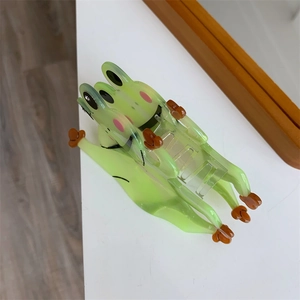 Detail einer durchsichtigen grünen Frosch-Haarklammer mit Augen und rosa Wangen