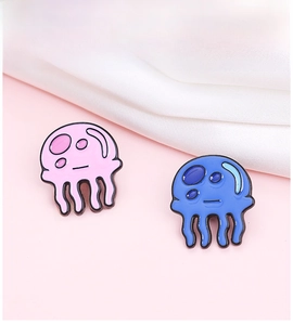 Detail view of cute pink and blue jellyfish enamel pins on pink background