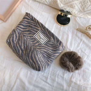 Detail of zebra pattern chenille makeup bag with Time to Party label on soft fabric