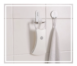Detail showing white fruit peeler hanging on minimalist wall hooks for kitchen storage