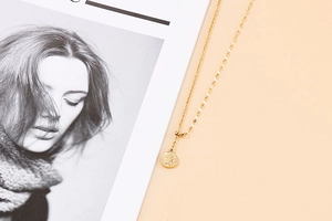 Detailed close-up of a golden stainless steel coin necklace with embossed portrait