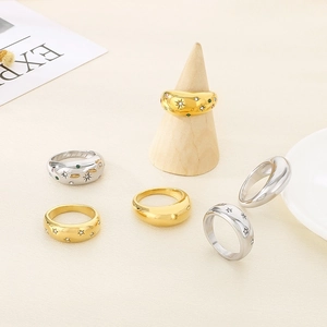 Detail of gold and silver minimalist rings with starburst engravings and zircon stones