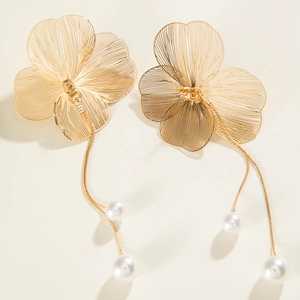 Détail de boucles d'oreilles fleur de ginkgo dorée avec longs pompons de perles