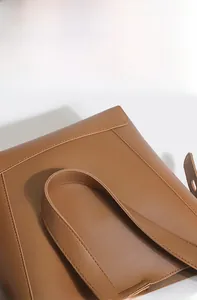 Close-up of brown leather bucket bag showing fine texture and meticulous stitching detail