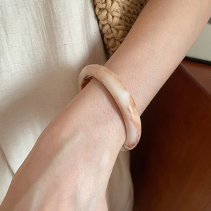 Detail of vintage hand-woven rattan style resin bangle with marble texture on wrist