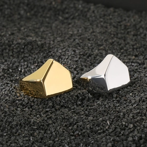 Polished gold and silver pyramid rings displayed on a textured dark stone background