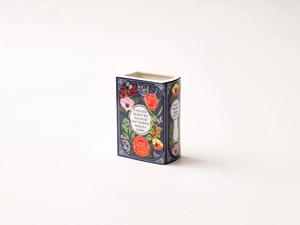Detailed view of book-shaped ceramic vase featuring floral art and a garden quote
