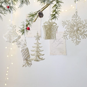 Glittery white Christmas ornaments set with snowflakes and bells on pine branches
