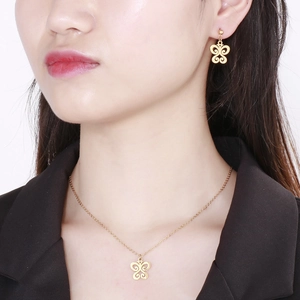 Ensemble collier et boucles d'oreilles papillon dorés porté par un mannequin