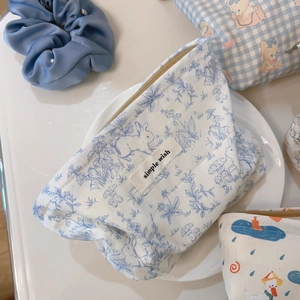 Close-up of blue bunny floral cotton makeup bag with a metal zipper on a ceramic plate