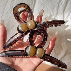 Detail view of large brown resin hair claws with marble texture circular bead accents