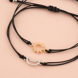 Detailed macro view of woven sun and moon charms on black friendship cord bracelets
