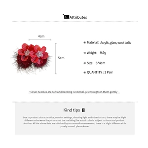 Detail view of red acrylic floral earrings with burgundy wool pompom and silver pins