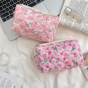 Close-up of pink quilted floral cosmetic bags with rose and tulip patterns and zipper detail