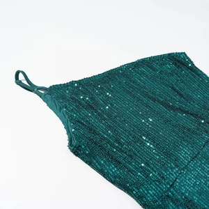 Detailed macro view of green sequins on a dress with an adjustable thin shoulder strap