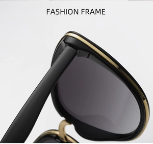 Close-up of golden metal hinges and black oversized frame detail on sunglasses