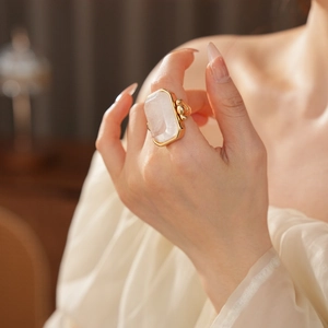 Dettaglio di un grande anello quadrato con pietra rosa e castone a perline dorate