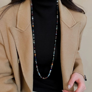 Detail shot of a bohemian long necklace with colorful multifaceted crystal beads on a model