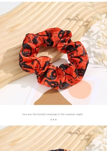 Close-up of Halloween hair scrunchie with orange satin fabric and festive pumpkin patterns