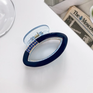 Close-up of navy blue hair claw clip with sparkling rhinestones and transparent blue handle