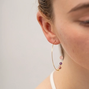 Golden C-shaped stainless steel hoop earrings with colorful beads on female model