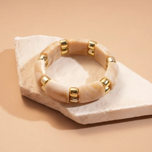 Detailed macro view of elastic bracelet with marble-textured beads and golden alloy spacers