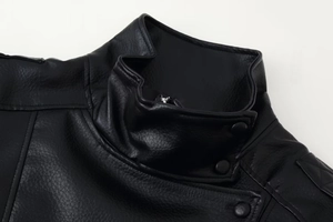 Detail of a black faux leather motorcycle jacket featuring a stand collar and metallic snap button